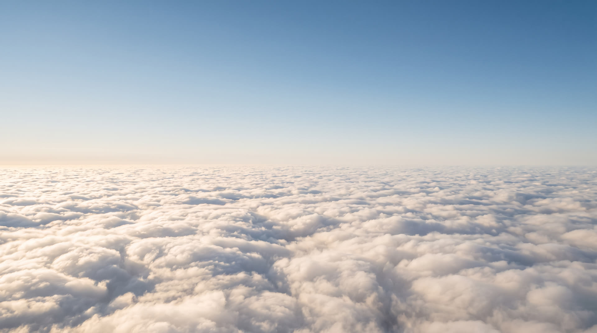 View from high altitude over an endless sunlit sea of clouds